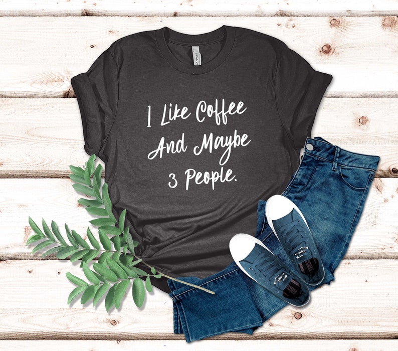 May include: A dark gray t-shirt with the text "I like coffee and maybe 3 people." printed in white.