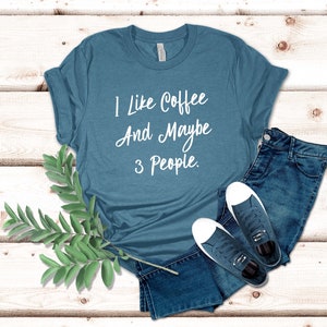 May include: A teal blue t-shirt with the text "I like coffee and maybe 3 people." printed in white.