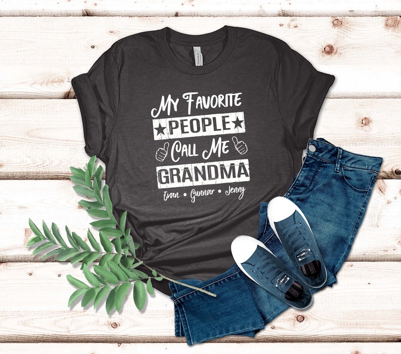 May include: A dark gray t-shirt with the text "My Favorite People Call Me Grandma" and the names "Evan, Gunnar, Jenny" printed on it.
