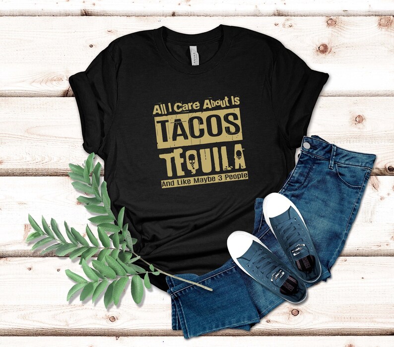 Pode incluir: Camiseta preta com um gr&aacute;fico dourado que diz "All I care about is tacos tequila and like maybe 3 people".