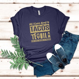Pode incluir: Uma camiseta azul marinho com o texto "All I care about is tacos tequila and like maybe 3 people" em letras douradas.