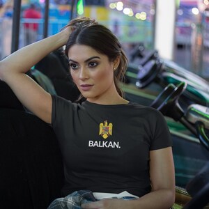 May include: A black t-shirt with a white print that says "BALKAN." The print also features a yellow and red eagle emblem.