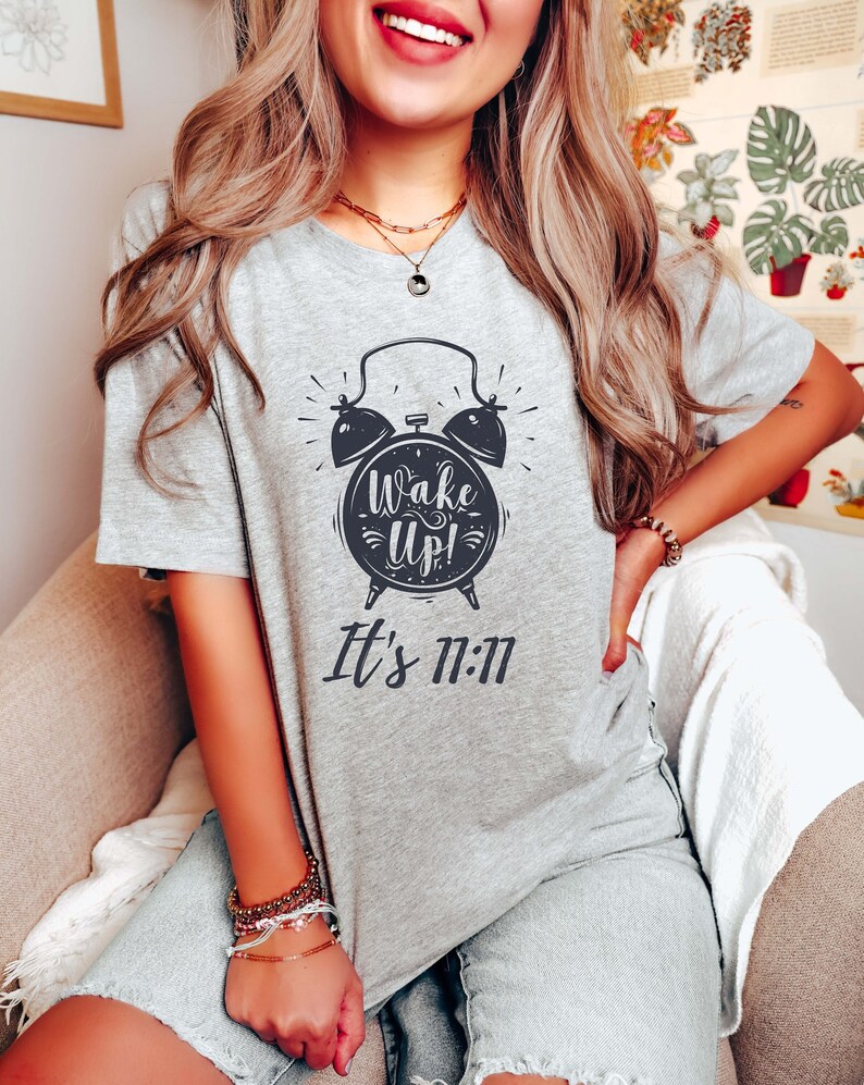 May include: Gray V-neck t-shirt with a black and white illustration of an alarm clock with the text "Wake Up! It's 11:11"