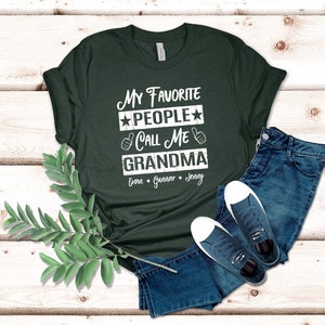 May include: A dark green t-shirt with the text "My Favorite People Call Me Grandma" in white with stars and thumbs up. The names Evan, Gunnar, and Jenny are listed below the text.
