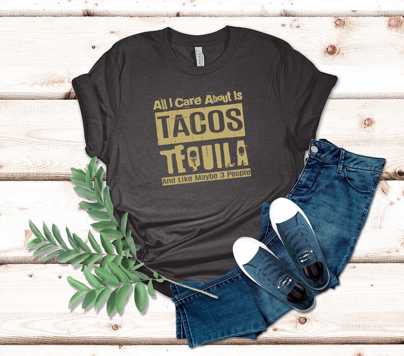 Pode incluir: Uma camiseta cinza escura com o texto "All I Care About Is Tacos Tequila And Like Maybe 3 People" em letras douradas.