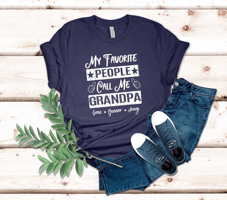 May include: Navy blue t-shirt with white text that reads "My Favorite People Call Me Grandpa" with three names listed below: Evan, Gunnar, Jenny.