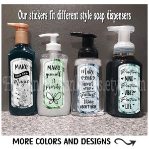 May include: Four soap dispensers with decorative labels. The labels feature different designs and text, including "Make your own magic", "Make yourself a priority", "Make your heart the prettiest thing about you", and "Positive mind, positive vibes, positive life".