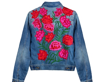 May include: A blue denim jacket with a floral embroidery design on the back. The flowers are pink and red with green leaves.