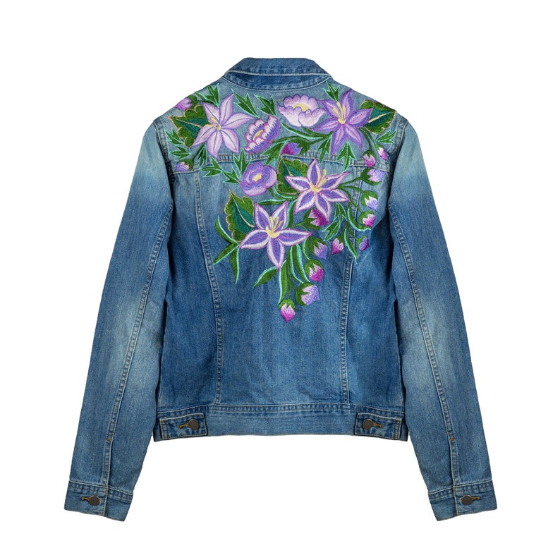 May include: A blue denim jacket with embroidered purple and green flowers on the back.