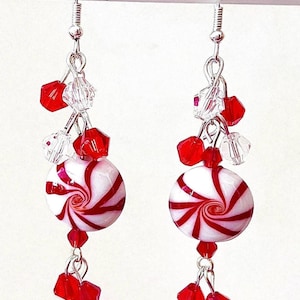 May include: Red and white candy cane swirl dangle earrings with clear and red crystal accents.