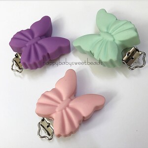 May include: Three silicone butterfly pacifier clips in purple, green, and pink. Each clip has a silver metal clasp.