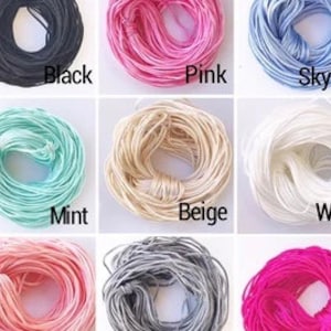 May include: Assortment of spools of embroidery floss in various colors, including black, pink, sky blue, mint, beige, white, light pink, gray, and fuchsia.