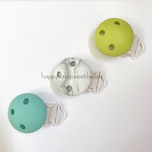 May include: Three silicone teethers with clip attachments. The teethers are in green, light green, and white with a marble pattern. The clips are white.