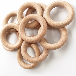 May include: A set of six natural wood rings, each with a smooth, unfinished surface. The rings are of varying sizes and are stacked together in a loose pile.