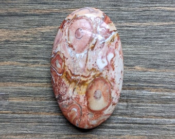 May include: A smooth, oval-shaped, red and white agate stone with a swirling pattern. The stone has a natural, polished finish.