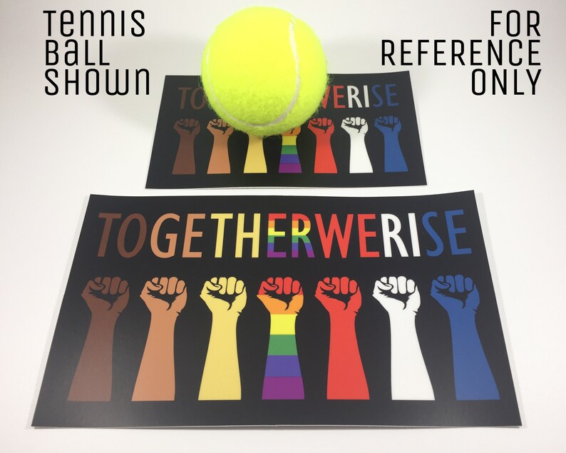 May include: Two black posters with the text "TOGETHER WE RISE" and illustrations of fists in various colors, including brown, yellow, red, white, and blue. A tennis ball is placed on top of one of the posters. The text "TENNIS BALL SHOWN" and "FOR REFERENCE ONLY" are also visible.