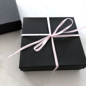 May include: A black gift box with a pink ribbon tied around it.