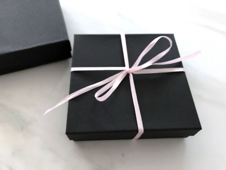 May include: A black gift box with a pink ribbon tied around it.