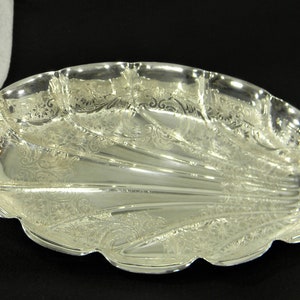 Puede incluir: Un plato de servir de plata con forma de concha con un diseño ornamentado.