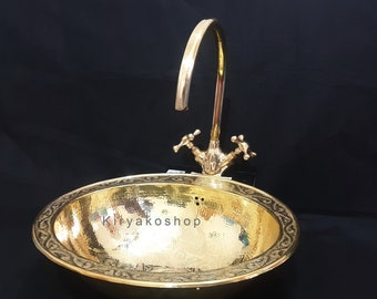 May include: A gold-colored brass sink with a decorative border and a matching faucet. The sink is round and has a hammered finish.