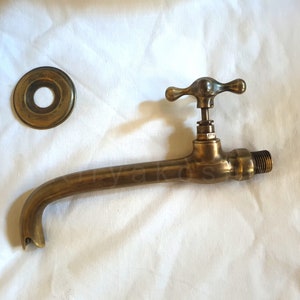 Pu&ograve; includere: Rubinetto in ottone con un becco lungo e una maniglia a forma di croce. Il rubinetto &egrave; fissato a una parete e ha una piastra di copertura rotonda decorativa.