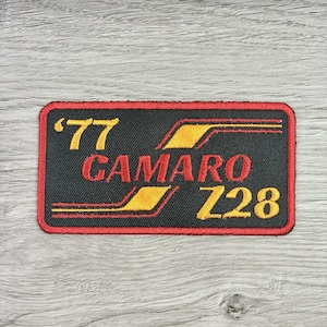 May include: Embroidered patch with a black background and a red border. The patch features the text "'77 CAMARO Z28" in yellow and red, with yellow accent lines. The patch is rectangular.
