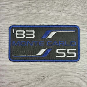 May include: Embroidered patch with a black background and a blue border. The patch features the text "'83 MONTE CARLO SS" in white and blue. The design includes blue and white accent stripes.