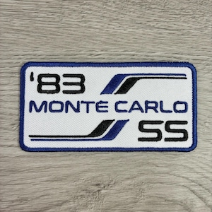 May include: '83 Monte Carlo SS embroidered patch. The rectangular patch features the text '83, Monte Carlo, and SS in black and blue. The patch has a white background with a blue border.