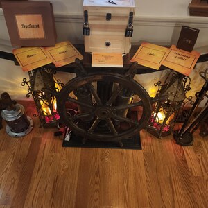 Puede incluir: Una caja de madera con cerraduras de combinaci&oacute;n, un tim&oacute;n de barco y varios accesorios, incluyendo letreros que dicen "Top Secret", "Items", "Hints", "Tools" y "Warning Labels". La escena est&aacute; iluminada con luz c&aacute;lida, sugiriendo una sala de escape o un juego tem&aacute;tico.