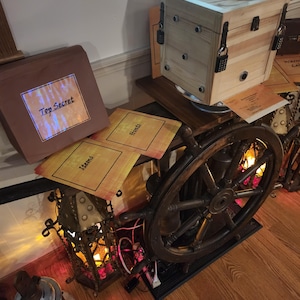 Puede incluir: Una caja de madera con m&uacute;ltiples cerraduras de combinaci&oacute;n, un tim&oacute;n y una linterna. La caja tiene un acabado de madera clara y tiene forma de cubo. El tim&oacute;n es de color marr&oacute;n oscuro. La linterna es ornamentada con un marco de metal y est&aacute; iluminada con un brillo c&aacute;lido. Las palabras "Top Secret" son visibles.
