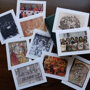 May include: A selection of square art prints depicting religious scenes, such as the Last Supper, in various artistic styles. The prints include black and white etchings and colourful illustrations. A green book is also present in the image.