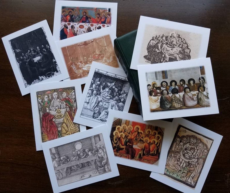 May include: A selection of square art prints depicting religious scenes, such as the Last Supper, in various artistic styles. The prints include black and white etchings and colourful illustrations. A green book is also present in the image.