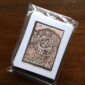May include: A pack of art prints in a clear plastic sleeve. The prints showcase a religious illustration with figures in a warm colour palette. The artwork depicts a central figure surrounded by others, with detailed linework and a vintage aesthetic.