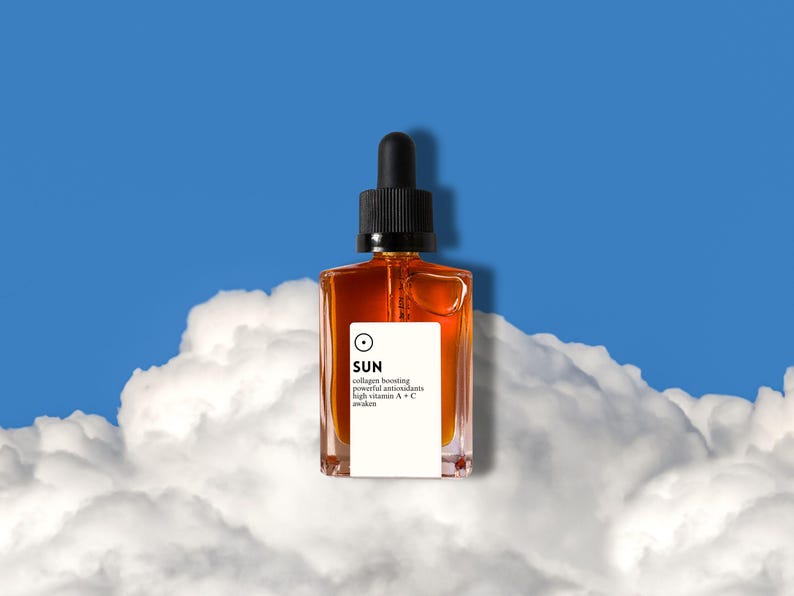 May include: A square amber glass bottle with a black dropper top, labeled "SUN" with text indicating collagen boosting properties. The bottle is set against a backdrop of fluffy white clouds and a bright blue sky.