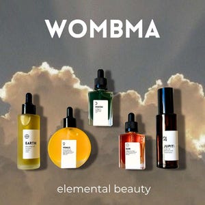 May include: A collection of six glass bottles with black droppers, each containing a different colored liquid. The bottles are labeled "EARTH", "VENUS", "MOON", "SUN", and "JUPITI". The text "WOMBA" and "elemental beauty" are also displayed.