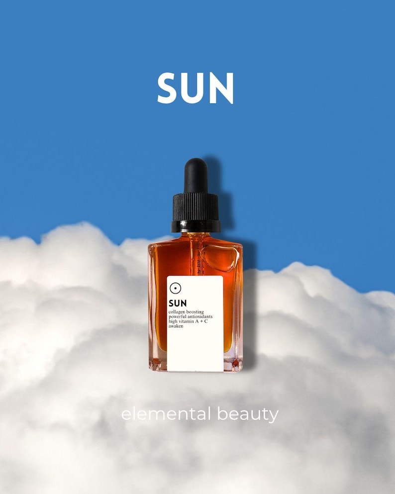 May include: A square amber-colored glass bottle with a black dropper top. The bottle has a white label with the word "SUN" and other text. The background is a blue sky with white clouds. The words "elemental beauty" are at the bottom.