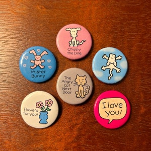 May include: Six colorful round buttons with different illustrations and text. The buttons feature a dog, a bunny, a cat, a flower, a bird, and a heart. The text on the buttons includes "Chippy the Dog", "Mister Bunny", "The Angry Cat Next Door", "Flowers for you", "I love you!"