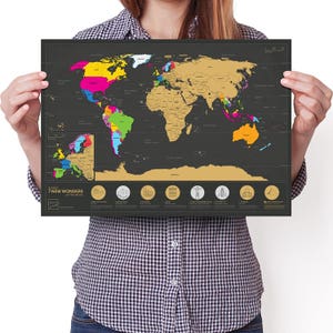 May include: A black world map with gold scratch-off areas, showing a colourful display of countries. The map includes an inset of Europe and icons representing the 7 New Wonders of the World. The text "Scratch 7 NEW WONDERS of the World" is visible.