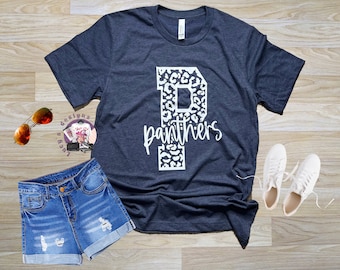 May include: A navy blue t-shirt with a white leopard print letter "P" and the word "Panthers" in white text.