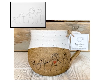 May include: A brown and white ceramic mug with a hand-drawn illustration of a family of five. The mug has a speckled glaze and a rounded shape. The illustration is in black ink and includes a red heart. The mug is sitting on a wooden surface. The text on the tag reads "Laura Lynn Pottery" and "LauraLynnPottery.etsy.com".