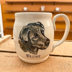 Puede incluir: Taza de cer&aacute;mica blanca con una ilustraci&oacute;n en blanco y negro de la cabeza de un perro. El nombre del perro, "Whitney", est&aacute; escrito debajo de la ilustraci&oacute;n.