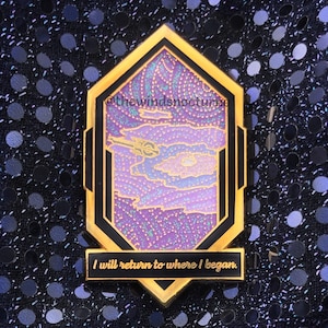 May include: A gold-colored pin with a black border and a purple and blue design. The pin features a stylized image of a spaceship and clouds. The text "I will return to where I began" is at the bottom.