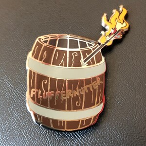 May include: A brown wooden barrel with a white band and the text "FLUFFERNUTTER" on the side. A yellow flame is sticking out of the top of the barrel.