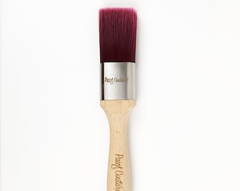 May include: A wooden-handled paint brush with a burgundy bristle head. The brush has a silver band with the text "Paint Couture!" engraved on it. The handle is also engraved with "Paint Couture!"