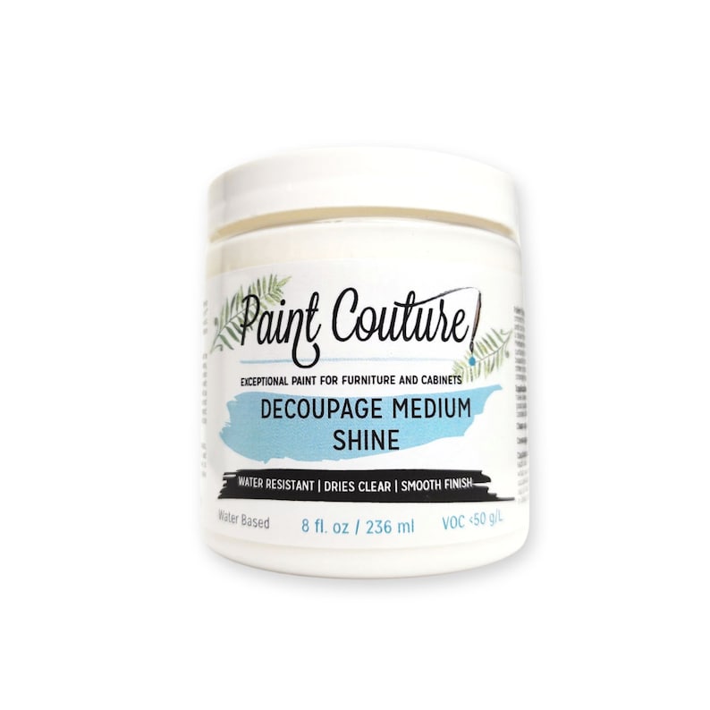 Op de afbeelding: Een witte pot Paint Couture Decoupage Medium Shine. De pot is gelabeld met de productnaam, een beschrijving van het product en de grootte van de pot: 8 fl. oz / 236 ml. De pot is op waterbasis en heeft een lage VOC.