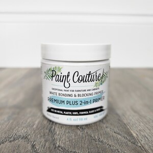 May include: A white jar of Paint Couture Premium Plus 2-in-1 Primer. The jar is labelled "Exceptional paint for furniture and cabinets. White bonding & blocking primer. Premium Plus 2-in-1 Primer. Use on metal, plastic, vinyl, formica, glass & more. Water based. 4 fl. oz/ 118 ml."
