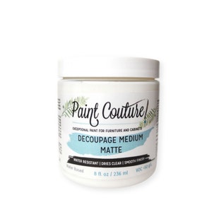 Puede incluir: Un tarro blanco de medio de decoupage con una etiqueta azul y blanca. La etiqueta dice "Paint Couture Pintura excepcional para muebles y armarios Decoupage Medium Mate Resistente al agua | Se seca transparente | Acabado liso A base de agua 8 fl. oz / 236 ml VOC < 50 g"