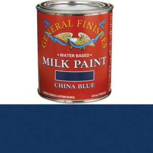 May include: A can of General Finishes Milk Paint in China Blue. The can is red with white lettering and a blue eagle logo. The can is labeled "Water Based" and "Milk Paint".