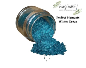 May include: A jar of teal blue glitter pigment labeled "Perfect Pigments Winter Green" with some of the glitter spilled out on a white surface.
