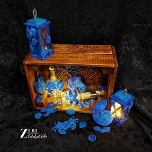 May include: A wooden crate filled with blue and gold nautical themed decorations. The crate is labeled "Bulldog Bourbon 38". The decorations include a bottle, a lantern, and a variety of seashells.